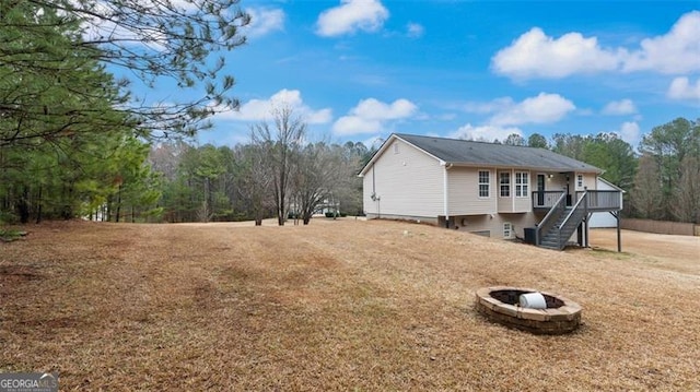 view of home's exterior with stairs, a wooden deck, and an outdoor fire pit