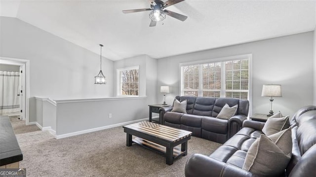 carpeted living area featuring baseboards, ceiling fan with notable chandelier, and vaulted ceiling