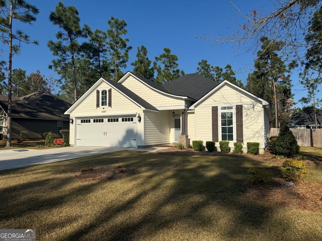 view of front of property featuring fence, concrete driveway, a front yard, a shingled roof, and a garage