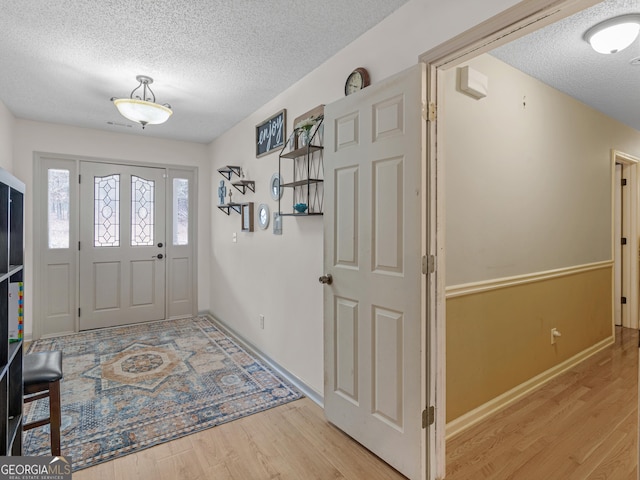 entrance foyer with baseboards, a textured ceiling, and light wood-style flooring