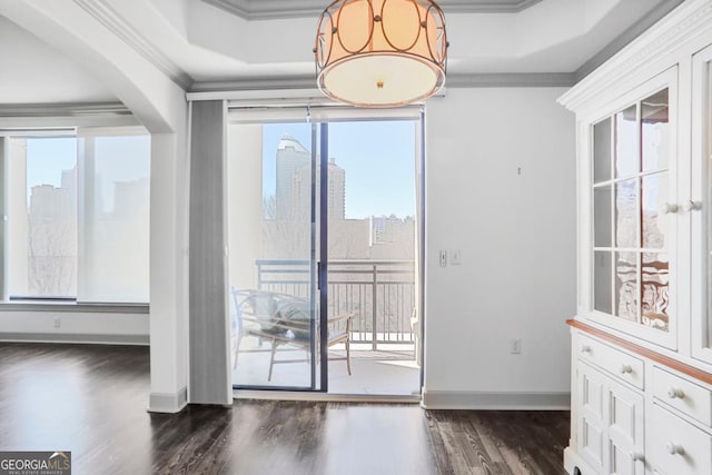 interior space with dark wood finished floors, crown molding, baseboards, and a raised ceiling