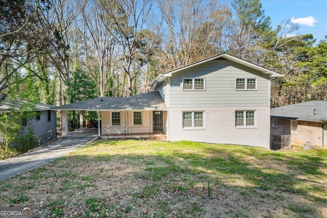 view of front of property with brick siding, driveway, an attached carport, and a front lawn