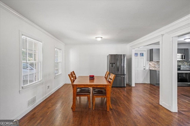 dining area featuring dark wood finished floors, visible vents, and crown molding