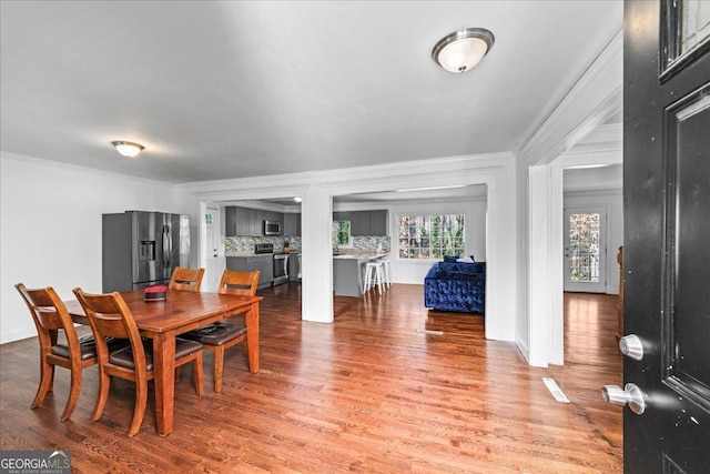 dining room featuring wood finished floors, baseboards, and ornamental molding