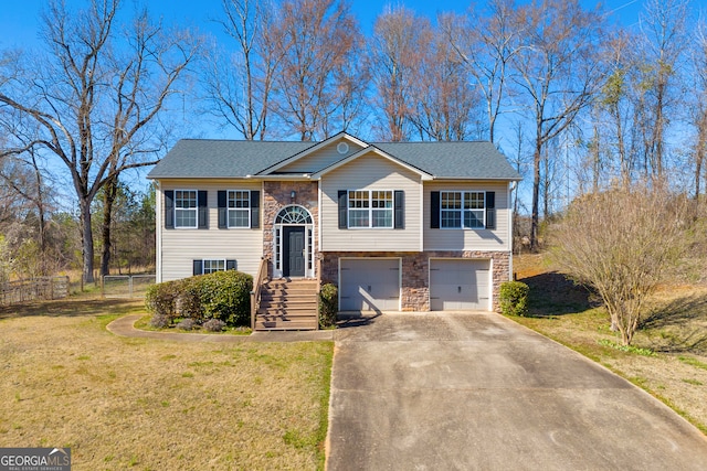 raised ranch with a front lawn, fence, a garage, stone siding, and driveway