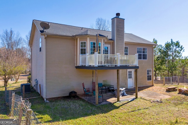 rear view of property with central air condition unit, a lawn, fence, a chimney, and a patio area