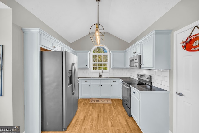 kitchen with a sink, decorative backsplash, appliances with stainless steel finishes, and vaulted ceiling