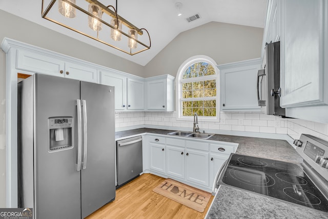 kitchen with visible vents, a sink, decorative backsplash, vaulted ceiling, and stainless steel appliances