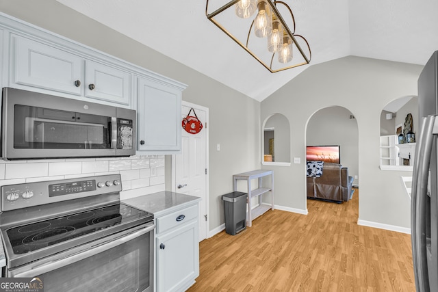 kitchen with lofted ceiling, light wood-style flooring, appliances with stainless steel finishes, decorative backsplash, and baseboards