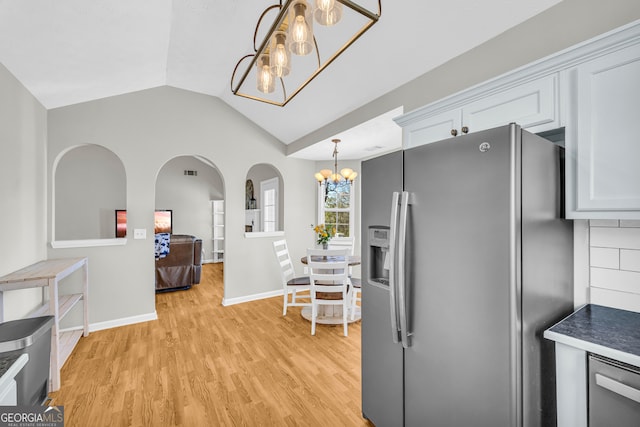 kitchen featuring a notable chandelier, backsplash, appliances with stainless steel finishes, light wood finished floors, and vaulted ceiling