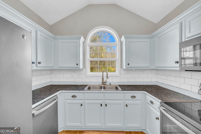 kitchen featuring lofted ceiling, tasteful backsplash, appliances with stainless steel finishes, and a sink