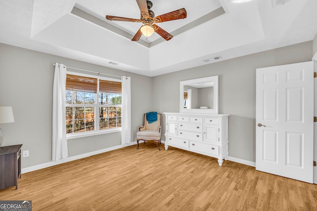 sitting room featuring visible vents, baseboards, a raised ceiling, and light wood-style floors