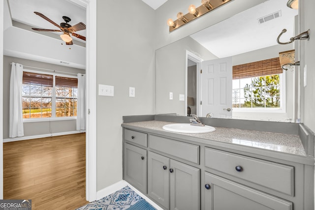 bathroom featuring visible vents, baseboards, wood finished floors, vanity, and a ceiling fan