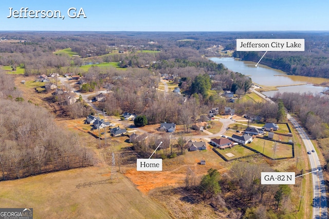 birds eye view of property with a wooded view and a water view