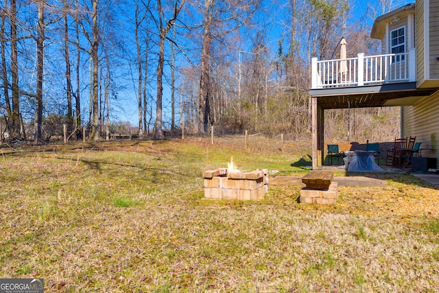 view of yard with a balcony, a fire pit, and fence