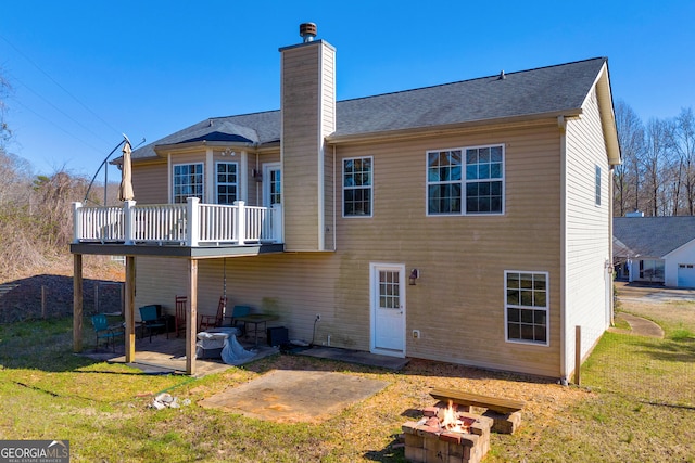 rear view of house featuring a chimney, a yard, an outdoor fire pit, and a patio