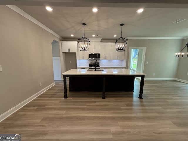 73 Hewett Rd, Pendergrass, GA 30567 - kitchen with a sink, a chandelier, ornamental molding, stainless steel microwave, and white cabinets