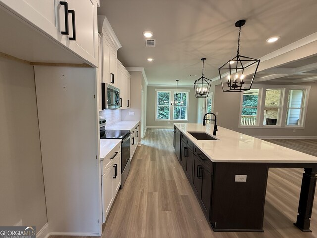 73 Hewett Rd, Pendergrass, GA 30567 - kitchen with appliances with stainless steel finishes, a sink, light wood finished floors, white cabinetry, and a center island with sink