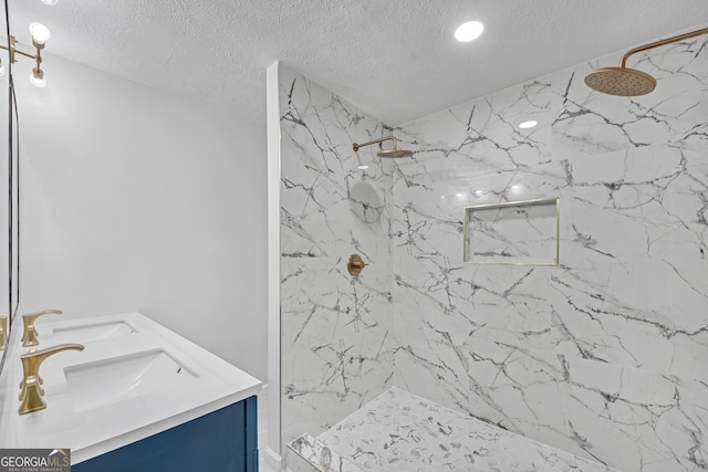 bathroom with a sink, double vanity, a marble finish shower, and a textured ceiling