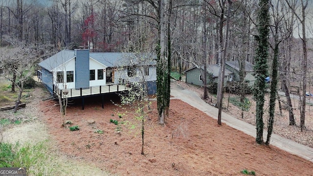 view of front facade with driveway, a wooded view, and a chimney