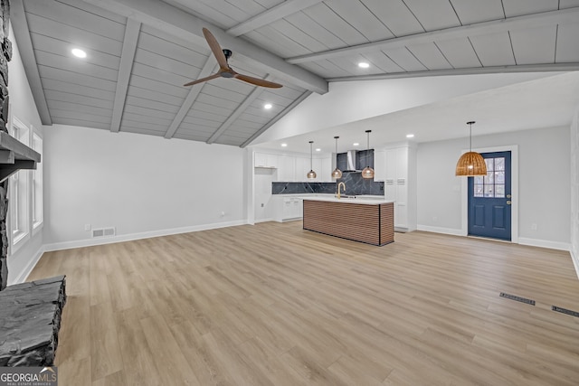 kitchen with visible vents, open floor plan, decorative backsplash, wall chimney exhaust hood, and a sink