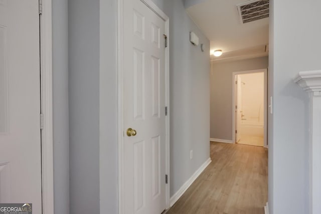 hallway featuring visible vents, baseboards, and light wood-style floors