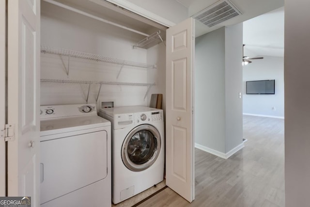 clothes washing area with visible vents, light wood-style flooring, a ceiling fan, separate washer and dryer, and laundry area