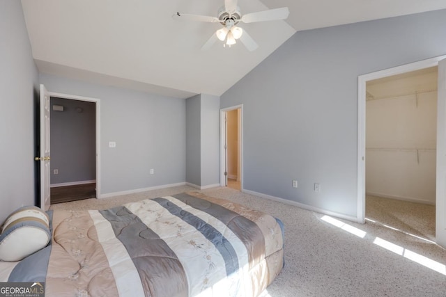 bedroom featuring ceiling fan, a walk in closet, baseboards, and vaulted ceiling