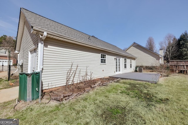 rear view of house with a patio area, fence, a lawn, and roof with shingles