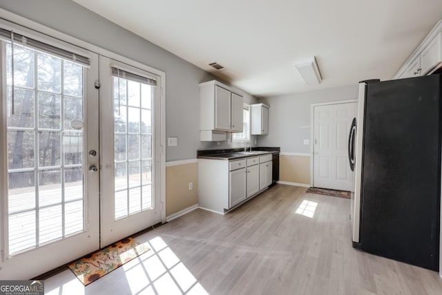 kitchen featuring visible vents, light wood finished floors, baseboards, freestanding refrigerator, and french doors