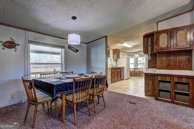 dining space with crown molding, light colored carpet, visible vents, and a textured ceiling