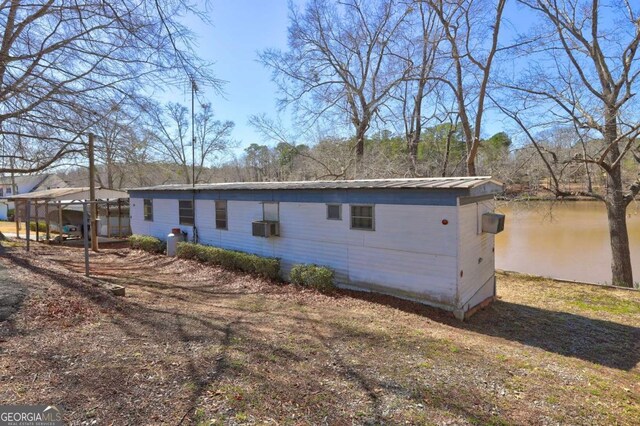 view of home's exterior with metal roof and a water view