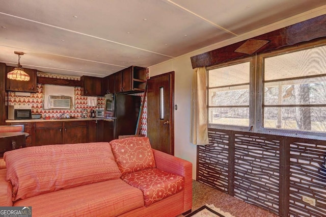 carpeted living room with a wall unit AC, a toaster, and a wealth of natural light