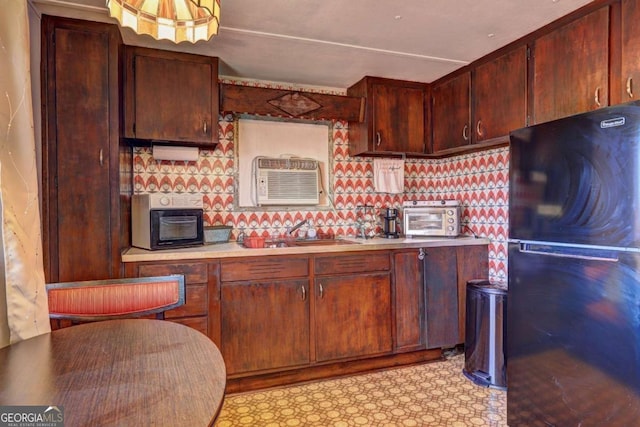 kitchen with a wall mounted AC, a toaster, freestanding refrigerator, light countertops, and tasteful backsplash