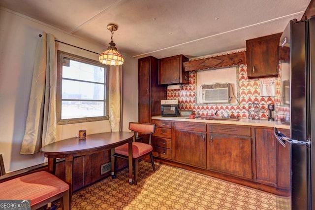 kitchen featuring a wall mounted air conditioner, visible vents, freestanding refrigerator, light countertops, and hanging light fixtures