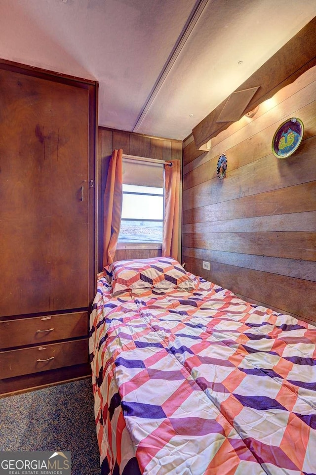 carpeted bedroom featuring wood walls