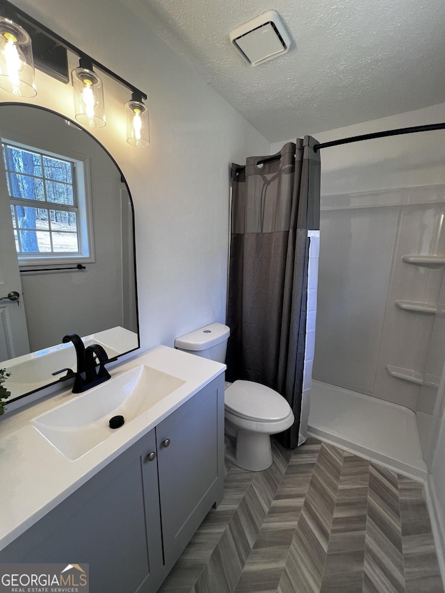 bathroom with visible vents, toilet, curtained shower, a textured ceiling, and vanity