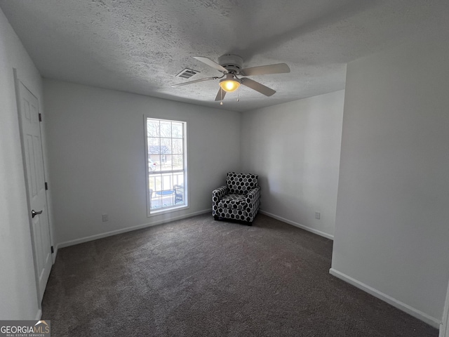 interior space featuring baseboards, visible vents, dark colored carpet, and a textured ceiling