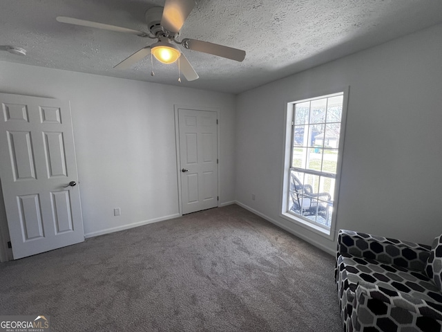 unfurnished bedroom with ceiling fan, carpet, baseboards, and a textured ceiling