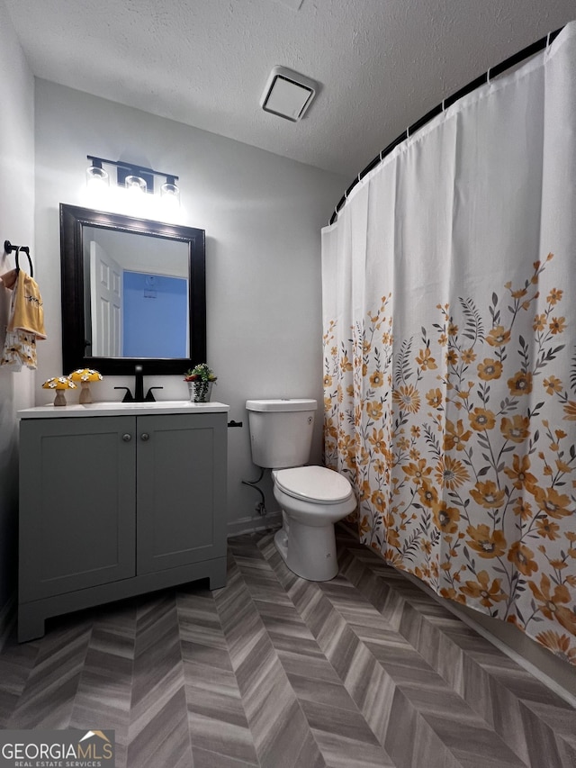 bathroom featuring vanity, toilet, a shower with curtain, and a textured ceiling