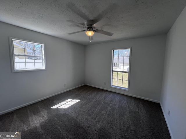 spare room featuring a textured ceiling, a ceiling fan, baseboards, and dark colored carpet