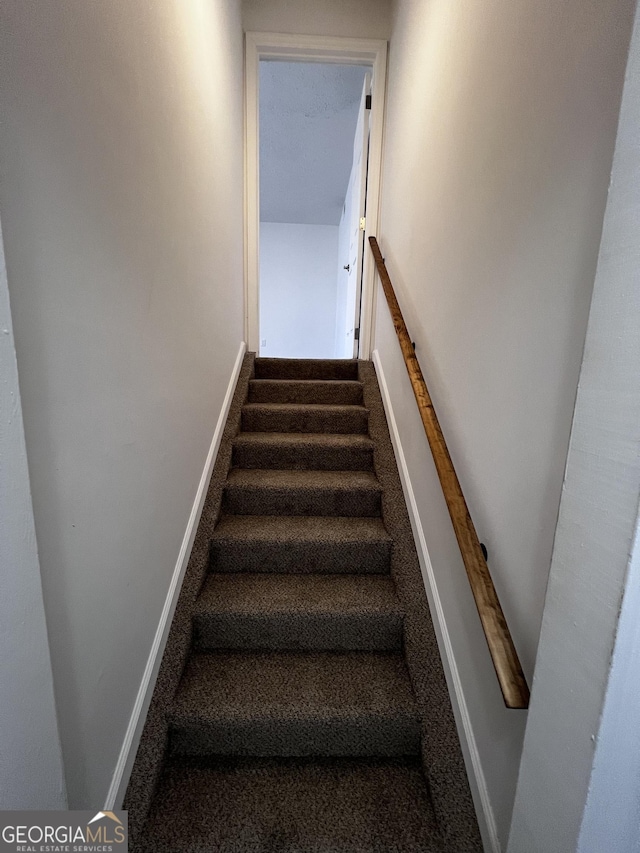 staircase featuring baseboards and carpet floors