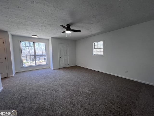 unfurnished bedroom featuring dark carpet, a textured ceiling, and baseboards