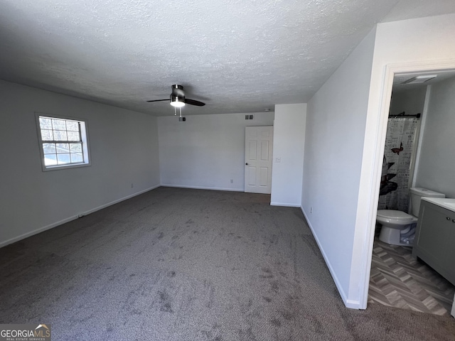 unfurnished bedroom with a ceiling fan, a textured ceiling, connected bathroom, carpet flooring, and baseboards