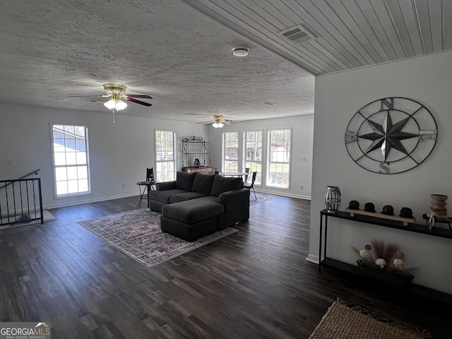 living area featuring plenty of natural light, dark wood-style flooring, and a textured ceiling