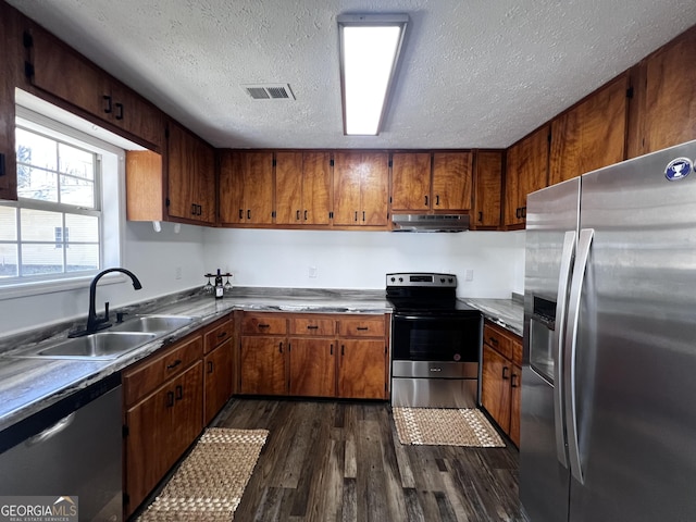 kitchen with visible vents, under cabinet range hood, dark wood finished floors, appliances with stainless steel finishes, and a sink