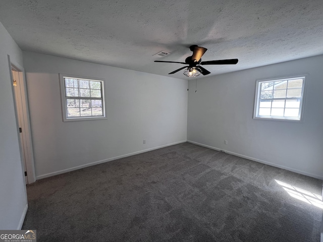 unfurnished room with a textured ceiling, baseboards, and dark colored carpet