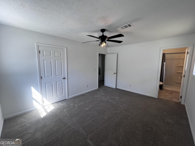 unfurnished bedroom with visible vents, dark carpet, a textured ceiling, and baseboards