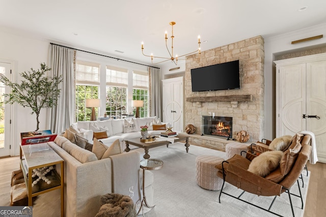 living room with a stone fireplace, an inviting chandelier, and light wood-style floors