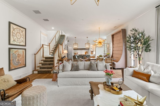 living area with an inviting chandelier, light wood-style flooring, recessed lighting, ornamental molding, and stairs